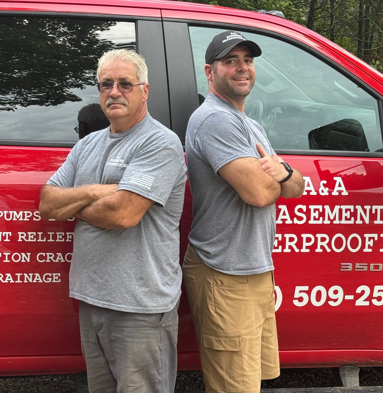 Alan and Alan Clement, father-and-son owners of A&A Basement Waterproofing, standing in front of their red A&A truck in Connecticut